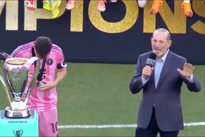 美職聯(lián)主席頒獎(jiǎng)致辭，一旁的梅西低頭翻看總冠軍獎(jiǎng)牌??